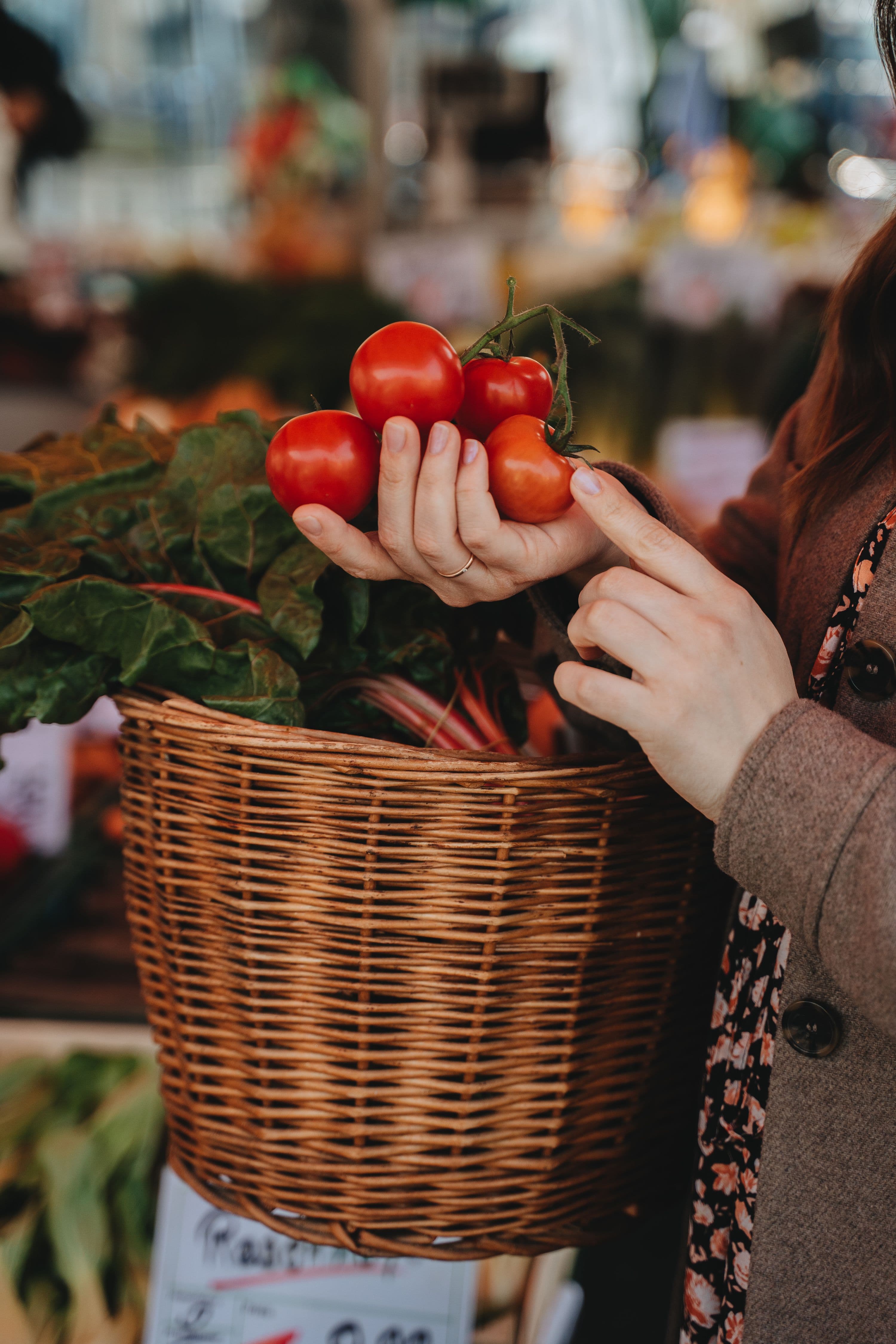 Woman selecting fresh tomatoes at a farmers market